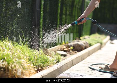 Nahaufnahme einer Frau, die Pflanzen mit Wassermangel im Garten mit der Hand tränkt Stockfoto