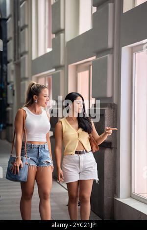 Zwei junge Frauen kaufen gerne Schaufensterläden in der Stadt ein und erkunden Modetrends und Verkäufe Stockfoto