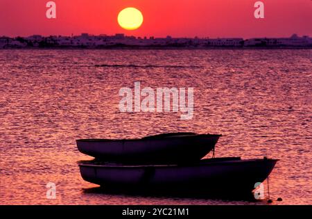 Dinghy-Boote und Sonnenuntergang an der Küste, Djerba, Tunesien Stockfoto