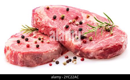 Rohe Ribeye-Steaks mit Pfeffer und Rosmarin isoliert auf weißem Hintergrund. Nahaufnahme. Stockfoto