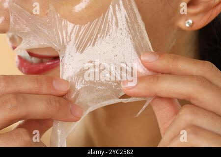 Lächelnde Frau, die die Gesichtsmaske abblättert, Nahaufnahme Stockfoto