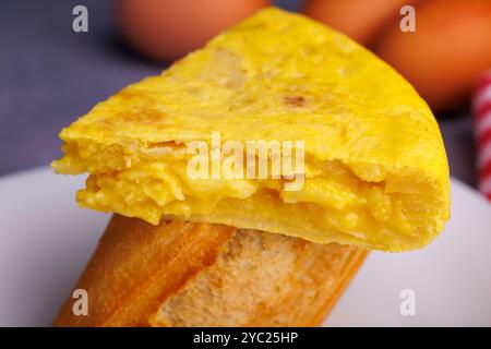 Spieß mit spanischem Omelett und Brot, Eier im Hintergrund, auf blauer Betonoberfläche. Draufsicht Stockfoto