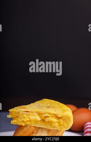 Omelette-Spieß mit Brot, Eier im Hintergrund auf einem blauen Betontisch. Detaillierte Überkopfansicht Stockfoto