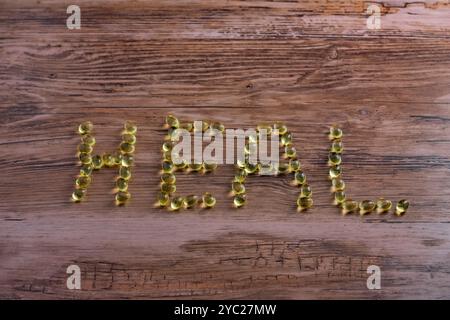 Eine hölzerne Oberfläche mit dem Wort "HEILEN", geschrieben mit gelben Pillen. Die Buchstaben bestehen aus kleinen, runden Objekten. Stockfoto