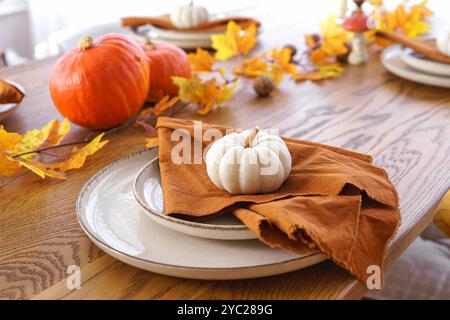 Herbst, Herbst, Halloween oder Thanksgiving festliche Tischdekoration. Gefallene Blätter, Kürbisse und Servietten auf Teller auf Holztischhintergrund. Stockfoto