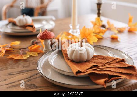 Herbst, Herbst, Halloween oder Thanksgiving festliche Tischdekoration. Gefallene Blätter, Kürbisse und Servietten auf Teller auf Holztischhintergrund. Stockfoto