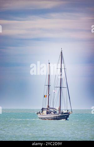 Ostend, Belgien, 6. Oktober 2024, Ein ruhiges Segelboot gleitet anmutig über das ruhige, türkisfarbene Wasser unter einem weichen und wunderschönen Himmel Stockfoto