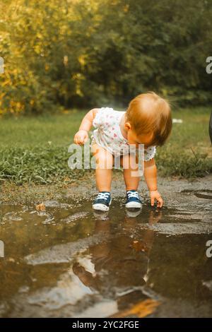 Ein Kleinkind, das Hände und Füße in eine Schlammpfütze legt Stockfoto