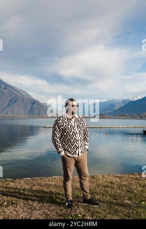 Stilvoller junger Mann, der vor Bergen und See steht Stockfoto