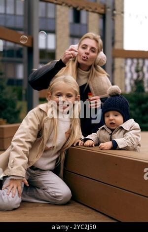 Mom verbringt Zeit mit zwei Kindern im Park, bläst Seifenblasen Stockfoto