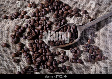Kaffeebohnen im Holzlöffel auf Sacktuch Hintergrund Stockfoto