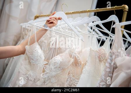 Oldenburg, Deutschland. Oktober 2024. Eine Frau schaut sich mehrere Brautkleider an einem Stand auf der Hochzeitsmesse an. Rund 60 Aussteller präsentieren an diesem Wochenende auf der Hochzeitsmesse in den Oldenburger Weser-Ems-Hallen die neuesten Trends der Branche. Quelle: Hauke-Christian Dittrich/dpa/Alamy Live News Stockfoto