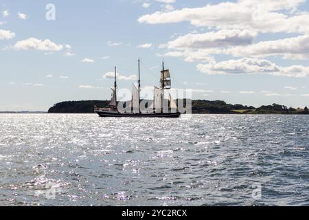 Ein wunderschönes Hochschiff segelt über das glitzernde Wasser bei Rügen, Deutschland, unter einem hellblauen Himmel mit verstreuten Wolken, der den Geist von verkörpert Stockfoto