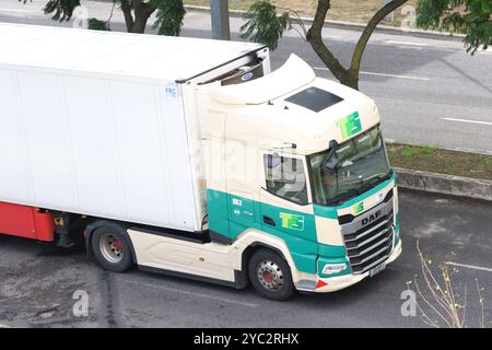 Weißer und grüner Auflieger fährt auf einer Straße in der Stadt Stockfoto