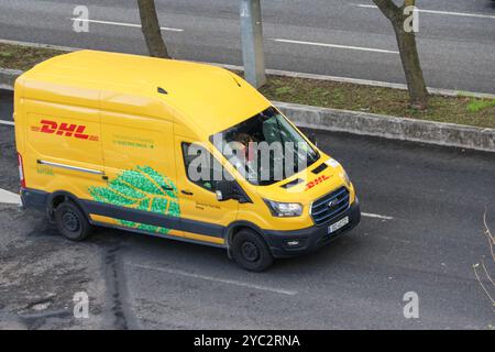 Gelber dhl ford Transit-Kurier, elektrischer Lieferwagen, der auf einer Straße fährt Stockfoto