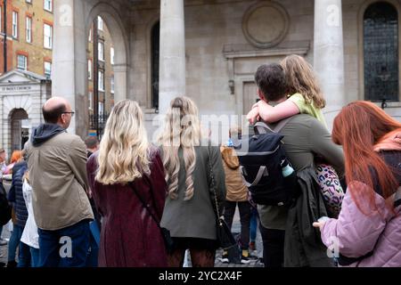 Rückansicht von hinten Familientouristen beobachten Straßenunterhalter auf dem Covent Garden Market im Herbst Oktober 2024 London England Großbritannien KATHY DEWITT Stockfoto