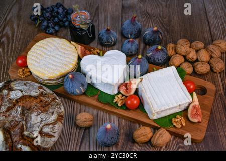 Auswahl an französischen Käsesorten aus der Normandie, AOP, Livarot, Neufchatel, Pont l'eveque, Roggenbrot, Feigen, Walnüsse, Trauben, Holundergelee Stockfoto