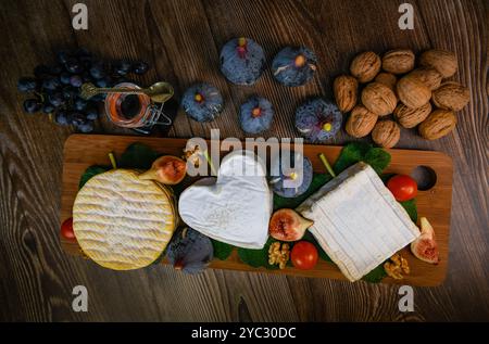 Auswahl an französischen Käsesorten aus der Normandie, AOP, Livarot, Neufchatel, Pont l'eveque, Roggenbrot, Feigen, Walnüsse, Trauben, Holundergelee Stockfoto