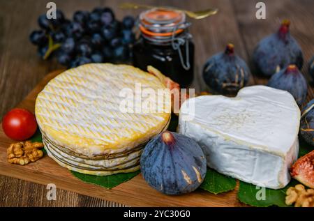 Auswahl an französischen Käsesorten aus der Normandie, AOP, Livarot, Neufchatel, Pont l'eveque, Roggenbrot, Feigen, Walnüsse, Trauben, Holundergelee Stockfoto