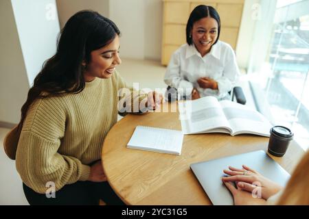 Zwei fröhliche Studenten genießen Kaffee und studieren gemeinsam auf dem Campus, was eine kollaborative und lebendige Lernatmosphäre fördert. Stockfoto