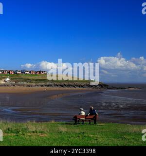 Ältere Ehepaare sitzen auf einer Bank und bewundern die Aussicht über Whitmore Bay, Barry Island, Cardiff, South Wales, Großbritannien. Vom Oktober 2024. Herbst Stockfoto