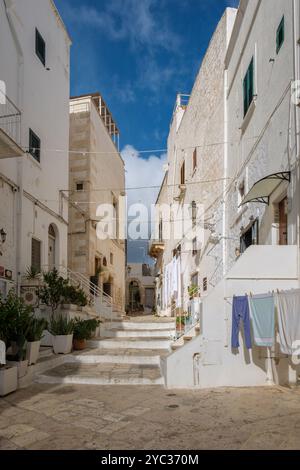 Ostuni Italien 18. September 2024 schlendern Sie durch die bezaubernden Straßen Apuliens, wo unberührte weiße Gebäude auf azurblauen Himmel treffen. Bunte Wäschegrippe Stockfoto