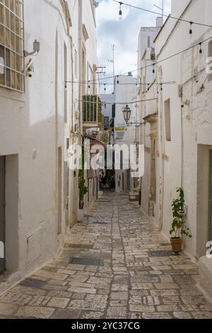 Ostuni Italien 18 September 2024 Eine ruhige, enge Straße in Apulien, Italien, bietet charmante weiß getünchte Gebäude und einladende Geschäfte. Stränge von li Stockfoto