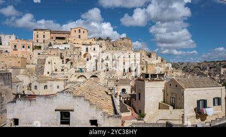 Eingebettet im Herzen von Apulien zeigt Matera Italien seine bemerkenswerten Höhlenhäuser und Steinarchitektur, eine zeitlose Mischung aus Geschichte und Schönheit vor dem Hintergrund flauschiger Wolken. Stockfoto