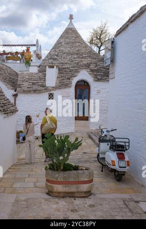 Alberobello Italien 18. September 2024 zwei Besucher schlendern durch die malerischen Straßen Apuliens, umgeben von berühmten Trulli-Häusern unter einem dramatischen Schauplatz Stockfoto