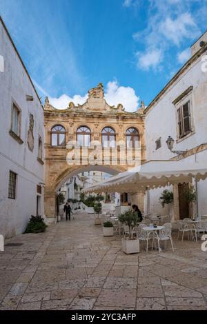 Ostuni Italien 18. September 2024 schlendern Sie durch die malerischen Straßen Apuliens, wo ein kunstvoller Bogengang weiß getünchte Gebäude verbindet. Unten ein gemütliches o Stockfoto