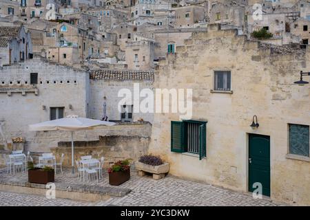 Im Herzen von Matera, Italien, erheben sich wunderschöne Steinhäuser steil und bilden eine atemberaubende Kulisse für den malerischen Essbereich im Freien. Stockfoto
