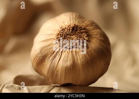 Roher Knoblauch auf zerknittertem beigem Papier, Nahaufnahme Stockfoto