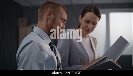 Porträt von zwei Finanzspezialisten oder professionellen Bankmitarbeitern, die Dokumente ansehen, Projektideen diskutieren und die Unternehmensstrategie Brainstorming erarbeiten. Männliche und weibliche Kollegen arbeiten in modernen Büros. Stockfoto