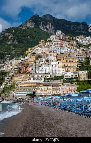 Farbenfrohe Häuser kaskadieren den Hügel in Positano hinunter, während sanfte Wellen am Kiesstrand schlängeln und einen perfekten Tag unter der Sonne von Amalfi bieten. Stockfoto