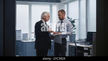 Zwei verschiedene Geschäftsleute diskutieren über Finanzmarktdaten, studieren Dokumente und Dokumente, sprechen über profitable Geschäfte mit Partnern und Geschäftsstrategie. Arbeiten in einem internationalen Finanzunternehmen. Stockfoto