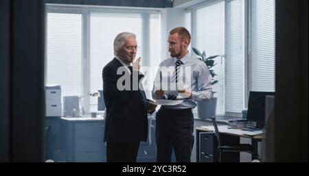 Zwei verschiedene Geschäftsleute diskutieren über Finanzmarktdaten, studieren Dokumente und Dokumente, sprechen über profitable Geschäfte mit Partnern und Geschäftsstrategie. Arbeiten in einem internationalen Finanzunternehmen. Stockfoto