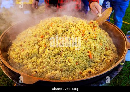 Türkisches Pilaw wird während des Kochens in einem großen gusseisernen Kessel gekocht Stockfoto