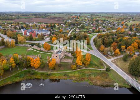 Farbenprächtiges Herbstlaub umgibt alte Ruinen in der Nähe einer malerischen Stadt und gewundenen Straßen. Stockfoto