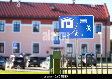 Ein Schild weist die Fahrer darauf hin, auf Kinder zu achten, die in der Nähe von Häusern und Fahrzeugen spielen. Stockfoto