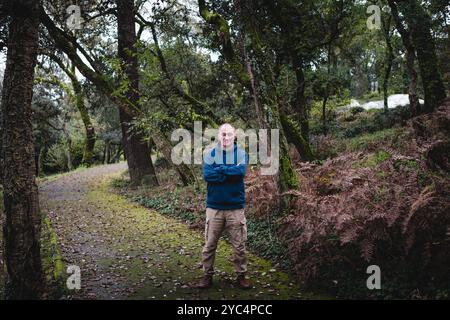 Ein Mann steht mit geschlossenen Augen auf einem Parkweg, umgeben von den goldenen Herbstlaub-Tönen, und genießt einen ruhigen Moment der Ruhe und Besinnung. Stockfoto