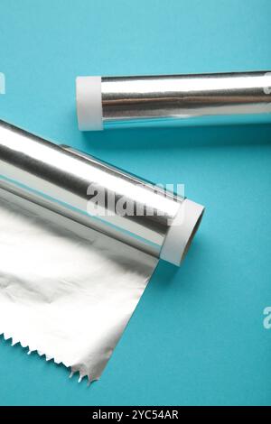 Rollen aus Aluminiumfolie auf blauem Hintergrund. Vertikales Foto. Draufsicht Stockfoto