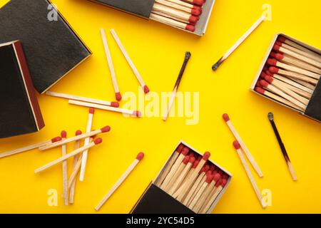 Schachtel mit Streichhölzern mit verbrannten Streichhölzern auf gelbem Hintergrund. Draufsicht Stockfoto