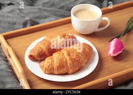 Frühstück im Bett mit Kaffee, Croissants und Tulpe auf Tablett. Draufsicht Stockfoto