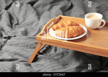 Frühstück im Bett mit Kaffee und Croissants auf Tablett. Draufsicht Stockfoto