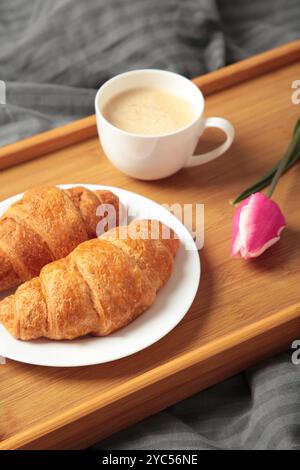 Frühstück im Bett mit Kaffee, Croissants und Tulpe auf Tablett. Draufsicht Stockfoto