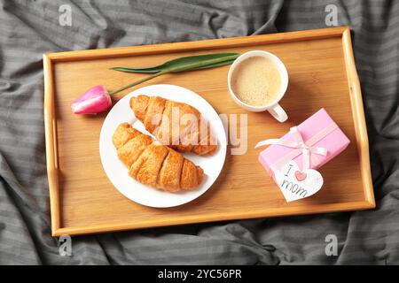 Froher Muttertag, wunderschönes Frühstück, Mittagessen mit einer Tasse Kaffee, frischen Croissants, Tulpe und Geschenk. Frühlingsferien, Familienbeziehungen. Draufsicht Stockfoto