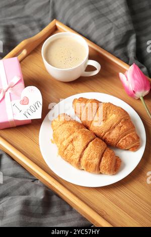 Froher Muttertag, wunderschönes Frühstück, Mittagessen mit einer Tasse Kaffee, frischen Croissants, Tulpe und Geschenk. Frühlingsferien, Familienbeziehungen. Draufsicht Stockfoto