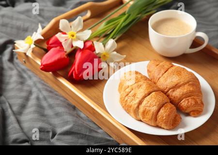 Frühstück im Bett mit Kaffee, Croissants und Tulpe auf Tablett. Draufsicht Stockfoto