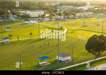 Schulkinder spielen beim Sporttraining im Schulstadion bei Sonnenuntergang ein Fußballspiel. Aktives Lebenskonzept. Stockfoto