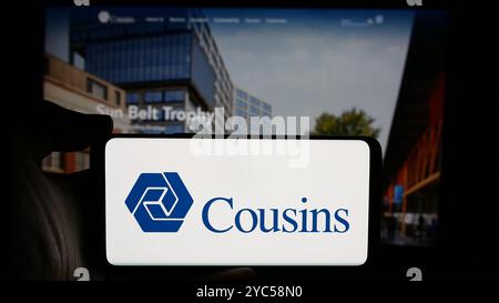 Person, die ein Mobiltelefon mit dem Logo der amerikanischen Immobilienfirma Cousins Properties Inc. Auf dem Bildschirm vor der Webseite hält. Schwerpunkt auf dem Display des Telefons. Stockfoto
